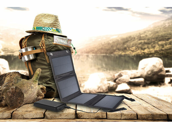 Mise en situation du chargeur solaire et de la batterie externe PB-195 posé contre un sac à dos de randonnée et d'un chapeau style Indiana Jones sur un pont en bois suspendu dans le vide au-dessus d'une falaise de montagne