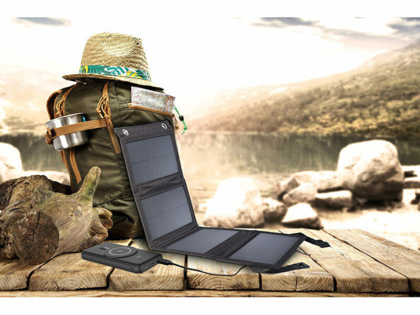 Mise en situation du chargeur solaire et de la batterie externe PB-170 posé contre un sac à dos de randonnée et d'un chapeau style Indiana Jones sur un pont en bois suspendu dans le vide au-dessus d'une falaise de montagne