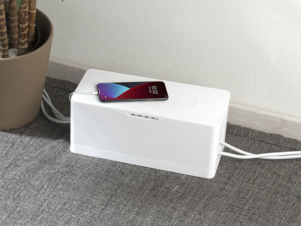 Boîte de rangement pliable pour multiprise coloris blanc mise en situation fermée avec smartphone