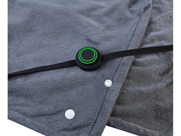 Plaid chauffant posé à plat avec câble d'alimentation posé dessus et boutons pression blancs pour ouverture et fermeture du compartiment à élément chauffant visibles de l'extérieur