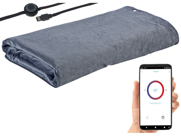 Couverture chauffante repliée avec câble d'alimentation USB et main tenant un smartphone sur lequel est affichée la température de chauffe