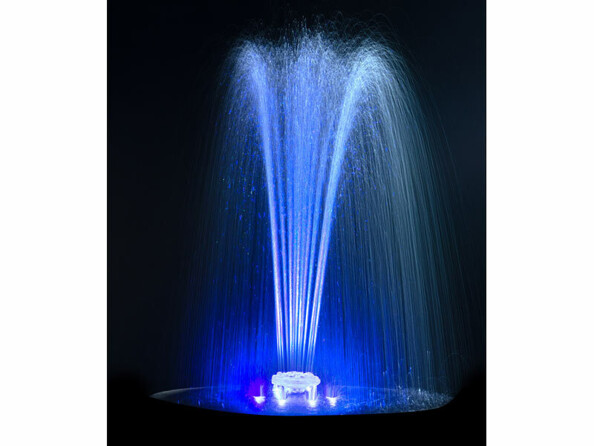 Jet d'eau éclairé par des LED bleues de la fontaine dans l'obscurité