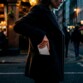 Mise en situation d'une femme en manteau dans la rue le soir glissant son téléphone portable dernière génération avec batterie de secours magnétique installée dans la poche de sa veste foncée