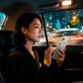 Femme d'affaire asiatique consultabt l'écran de son smartphone équipée d'une batterie externe à deux mains dans un taxi engagé dans le trafic routier