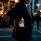 Mise en situation d'une femme en manteau dans la rue le soir glissant son téléphone portable dernière génération avec batterie de secours magnétique installée dans la poche de sa veste foncée