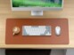 Mise en situation du tapis de bureau grand format couleur brun dans un setup informatique avec écran PC, clavier sans fil, souris sans fil et tasse de café sur un bureau en bois clair