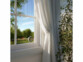 Capteur thermo-hygromètre digital blanc fixé sur une fenêtre à meneaux avec plante verte en arrière-plan