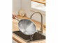 Wok en acier inoxydable 28 cm lavé dans un évier sous un filet d'eau