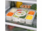 Boîte de conservation avec 8 compartiments amovibles remplie d'ingrédients vue dans un frigo