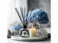 diffuseur de parfum à bâtonnets sur une table avec des bougies et des hortensias 
