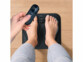Appareil de massage EMS pour pieds avec personne dessus et télécommande