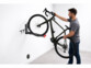 Personne accrochant son vélo sur le support mural orientable