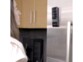 Jeune femme regardant le contenu affiché sur l'écran de son téléphone fixé sur la porte d'un frigo à hauteur de ses yeux