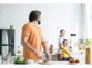 Mise en situation d'une famille de deux parents avec enfant faisant la cuisinre avec le détecteur de CO2 fixé au mur