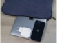 Mise en situation de l'adaptateur secteur USB-C/USB-A posé sur un MacBook sorti de sa sacoche de protection à côté d'un iPhone
