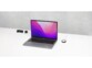 Setup de bureau avec supports autocollants pour câble noir, PC portable ouvert et allumé sur l'écran d'accueil et station de chargement à induction MagSafe avec housse de protection magnétique antidérapante