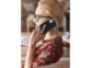 Jeune femme blonde à lunettes avec haut aux couleurs d'automne téléphonant avec un smartphone Apple avec coque de protection noire à l'oreille