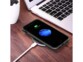 Chargement sans fil sur station de charge par induction USB d'un iPhone avec coque de protection intégrale à côté d'un PC portable ouvert
