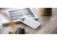 Mise en situation d'un iphone 13 avec coque blanche transparente posée de biais sur un livre sur un bureau en bois