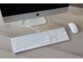 Mise en situation du clavier ergonomique filaire branché à un Mac éteint à côté d'une souris blanche sans fil sur un bureau en bois clair