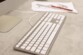 Vue de biais sur le périphérique filaire avec câble USB-C pour Mac coloris blanc et argent posé sur un bureau devant des fournitures de bureau et un écran d'ordinateur