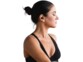 Jeune femme sportive en débardeur noir avec cheveux attachés en chignon, les yeux fermés et écoutant de la musique sans fil via une oreillette