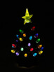 Sapin céramique illuminé dont les ampoules irradient sur fond noir