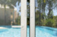 Mise en situation du capteur de porte fixé sur une porte-fenêtre ouverte menant à une piscine, avec sécurité anti-sabotage intégrée : avertissement par application si le capteur est retiré