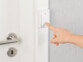 Mise en situation de la sonnette fixée sur le cadre d'une porte avec une main appuyant sur le bouton cinétique