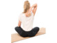 Femme assise en tailleur sur un tapis de yoga en liège entrain de se masser le dos au niveau de la colonne vertébrale à l'aide de la balle de massage simple en liège