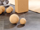 Boules de liège de deux diamètre différents (6,5 et 10 cm) posées sur le sol carrelé noir d'une pièce à côté d'un tapis de sol et d'une brique en liège