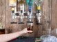 Mise en situation d'une personne se servant un verre d'alcool via le porte-bouteille mural fixé sur un mur de lambris en bois
