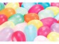 Plusieurs dizaines de ballons de baudruche multicolores gonflés et entassés les uns contre les autres formant un fond coloré