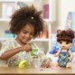 Une petite fille qui mixe la nourriture de sa poupée Poupée interactive "Baby Alive Mange à la cuillère".