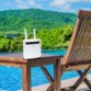 Routeur wifi Strong posé sur une table de salon de jardin en bois, au bord de la piscine avec forêt à perte de vue et chaîse en bois à côté de la table