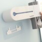 Distributeur de dentifrice avec stérilisateur UV et support adhésif pour installation facile.
