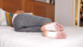 Femme en débardeur blanc et legging gris tacheté dormant allongée sur le côté gauche dans un lit avec deux patchs détox au bambou sur les pieds