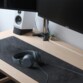 Mise en situation du casque filaire NIMA posé sur un tapis de bureau noir en tissu devant un écran d'ordinateur Asus éteint et une enceinte grise et noire
