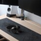 Mise en situation du casque filaire NIMA posé sur un tapis de bureau noir en tissu devant un écran d'ordinateur Asus éteint et une enceinte grise et noire