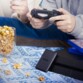 Adolescent jouant à la console avec à côté un bol de popcorn et une console de jeu avec le disque dur SSD Transcend posé contre