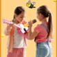 Deux petites filles devant un fond jaune orangé dont une jouant de la guitare et une chantant dans le micro du kit karaoké Maya CGV en dessous d'une petit abeille dessinée