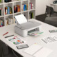 Mise en situation de l'imprimante jet d'encre Canon Pixma TS3551i posée sur une table de travail dans une salle d'étude avec une multitude de documents éparpillés sur la table