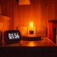 Lampe-ampoule à lévitation posée sur une table de nuit comme lampe de chevet à l'éclairage jaune tamisé à côté d'un réveil à écran numérique affichant 01:56