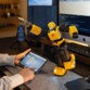 Homme contrôlant la figurine connectée interactive Transformers G1 Bumblebee à partir d'une application mobile sur tablette devant un MacBook