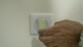 Main d'une personne collant une petite bande de ruban adhésif fluorescent sur un interrupteur blanc