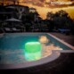 Siège flottant d'une lumière verte fluorescente dans une piscine d'un logement de vacances à la nuit tombée