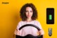 Femme aux cheveux bruns frisés simulant la conduite avec un volant entre les mains avec le chargeur allume-cigare illustré, un voyant du niveau de charge d'une batterie et logo Energizer