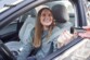 Jeune femme souriante sur le siège conducteur d'un véhicule fenêtre ouvert avec une main lui tendant le chargeur allume-cigare Energizer