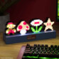 Décoration lumineuse Super Mario Bros avec 4 personnages éclairés (Mario, champignon, fleur et étoile) dans un setup gamer