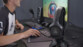 Adolescent en t-shirt assis à un bureau entrain de jouer sur PC souris en main avec micro filaire, clavier rétroéclairé et casque audio The G-Lab sur support à côté de lui